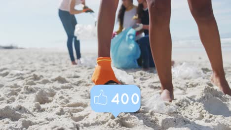 Animation-of-falling-social-media-like-icons-over-diverse-women-picking-up-rubbish-from-beach