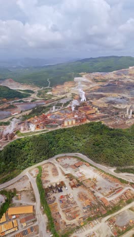 aerial view of pueblo viejo mine by barrick gold in cotuí - industrial structures with plumes of smoke. vertical shot