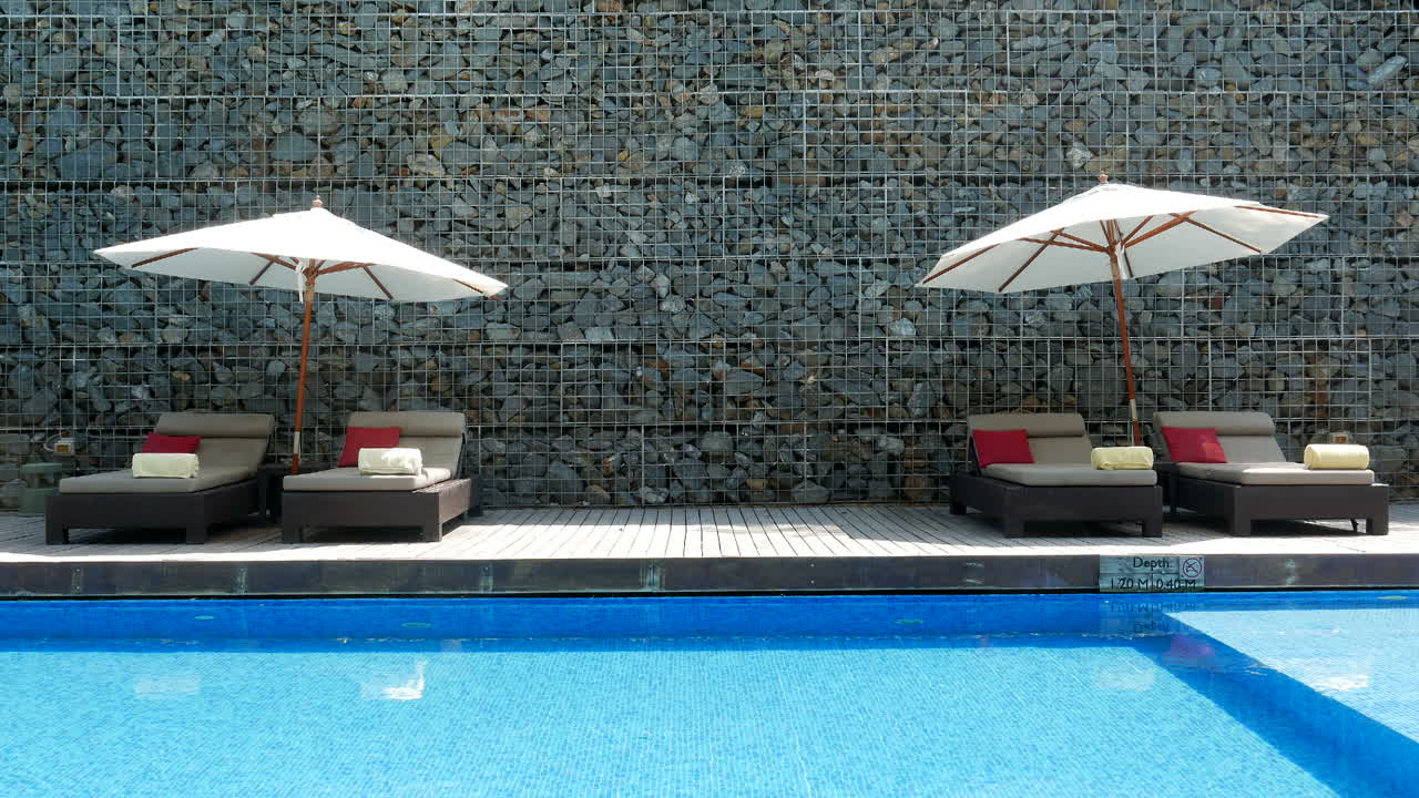 Luxurious pool side deck loungers with umbrellas and crystal blue water at a tropical resort