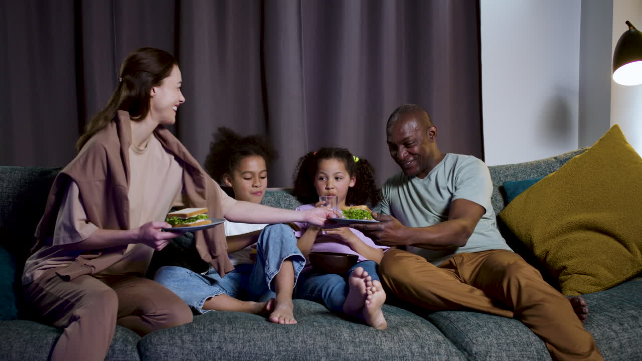 Bambini con i genitori che guardano un film a casa.
