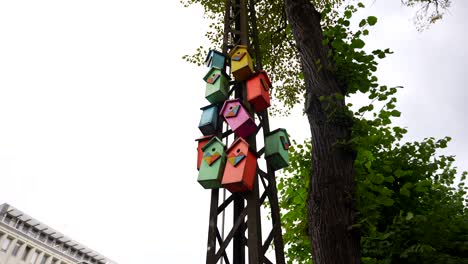 low angle shot, a row of colorful wooden birdhouses suspended on a pole along the street