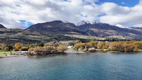 aerial footage captures glenorchy's serene landscape with mountains, lake, and vibrant autumn foliage under a partly cloudy sky