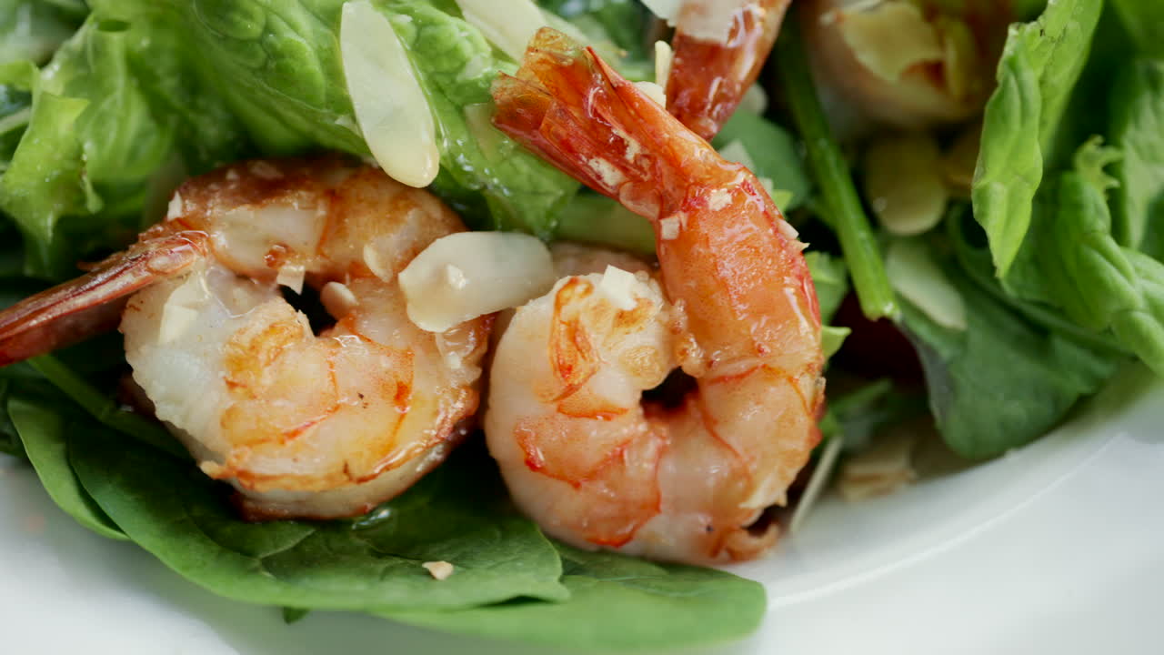 Close up of shrimp served on a fresh green salad with toppings