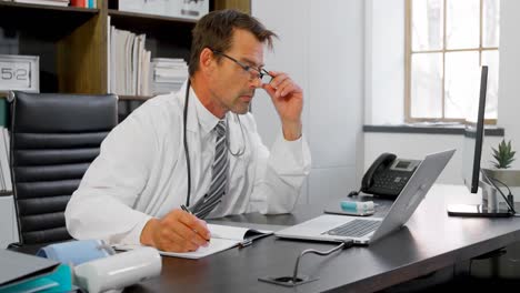 médico mirando la computadora portátil en su escritorio 4k