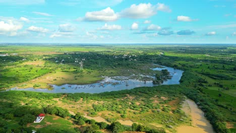 lush green landscape with winding river, clouds casting shadows, sunny day, aerial view