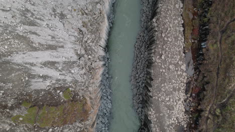 bird's eye view flying over basalt columns, river in studlagil canyon, iceland
