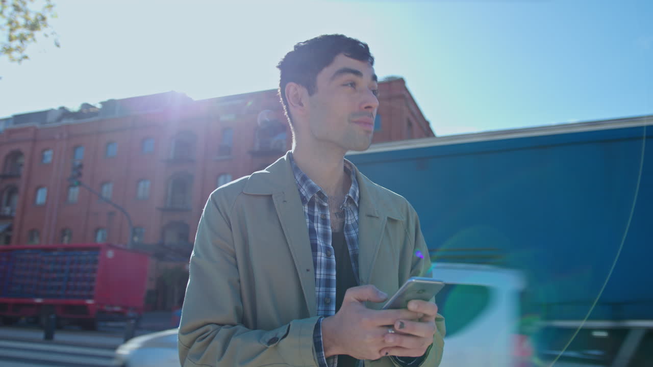 Young Man Typing Text Message on Phone and Looking Around at City Street