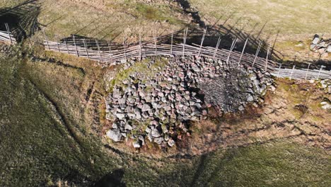 aerial shot of ancient nordic farm fence in a agricultural field with stone rock pile below