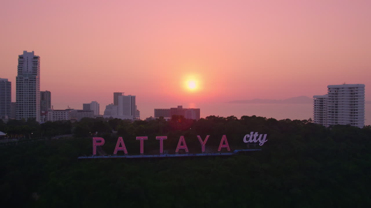 Vuela desde la puesta de sol hasta el letrero iluminado de Pattaya City en la colina