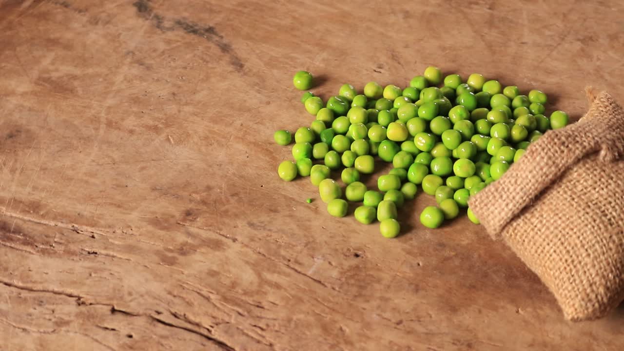 una vista de guisantes verdes colocados sobre un fondo de madera