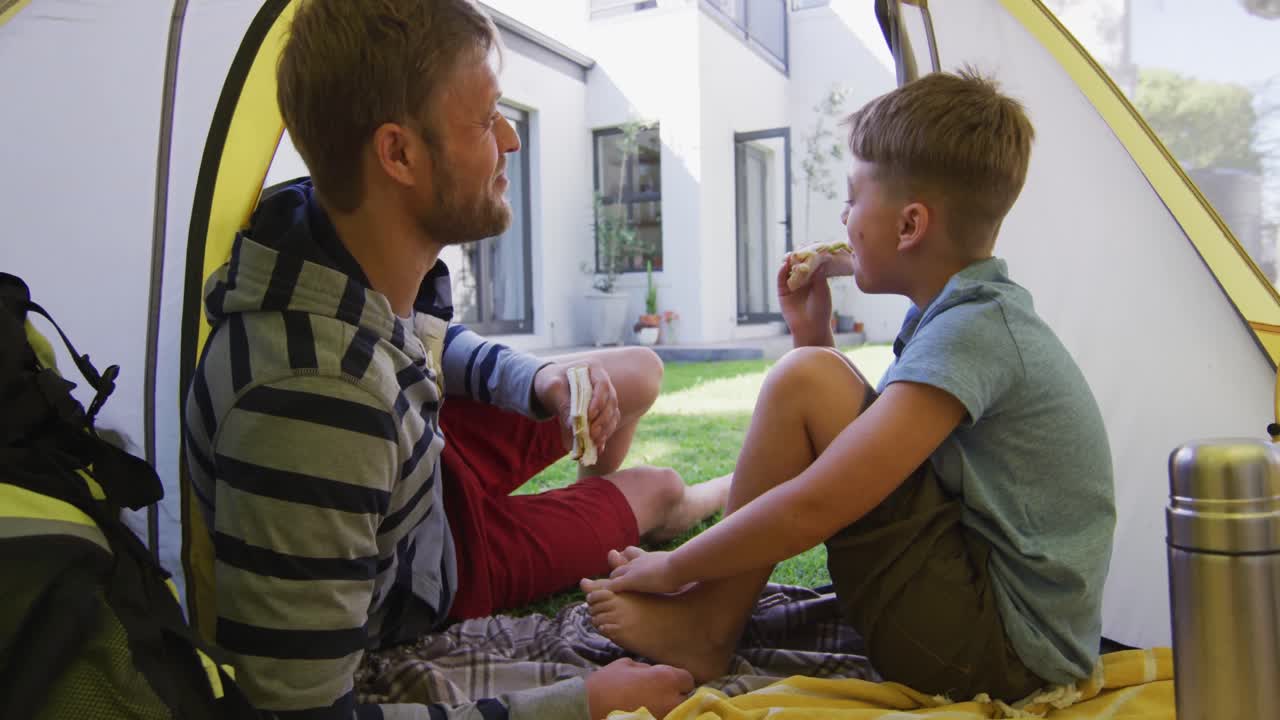 hombre caucásico acostado en una tienda con su hijo en el jardín