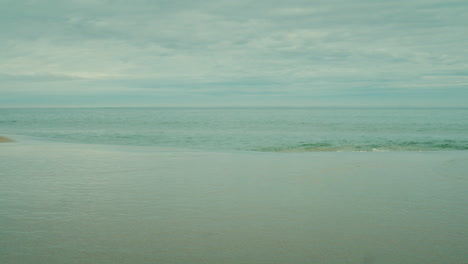 Slow-panning-shot-of-small-waves-rippling-onto-the-shore-at-Borestranda,-Norway