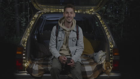 man relaxing in car trunk at night