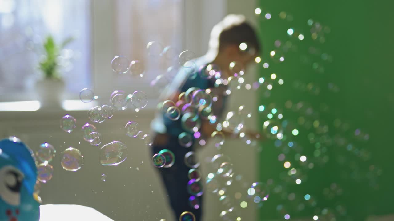 Energetic boy catching bubbles. Young child catching soap bubbles inside the room