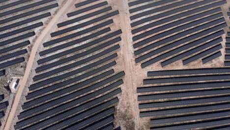 Vista-De-Arriba-Hacia-Abajo-Drone-Sobre-Parque-De-Energía-Solar-Fotovoltaica-Paneles-De-Fila-Colinas-Inclinadas