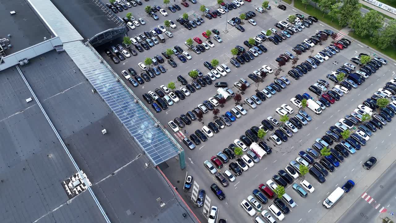 un ocupado estacionamiento del centro comercial con filas de coches estacionados, vista aérea