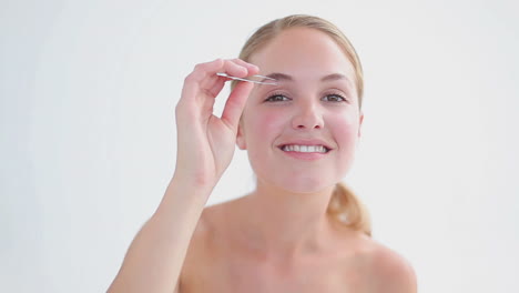 blonde woman plucking her eyebrows