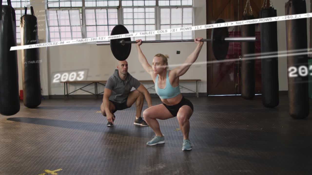 Female lifter lifting bar overhead descending to squat for coach spotting years sliding over gym