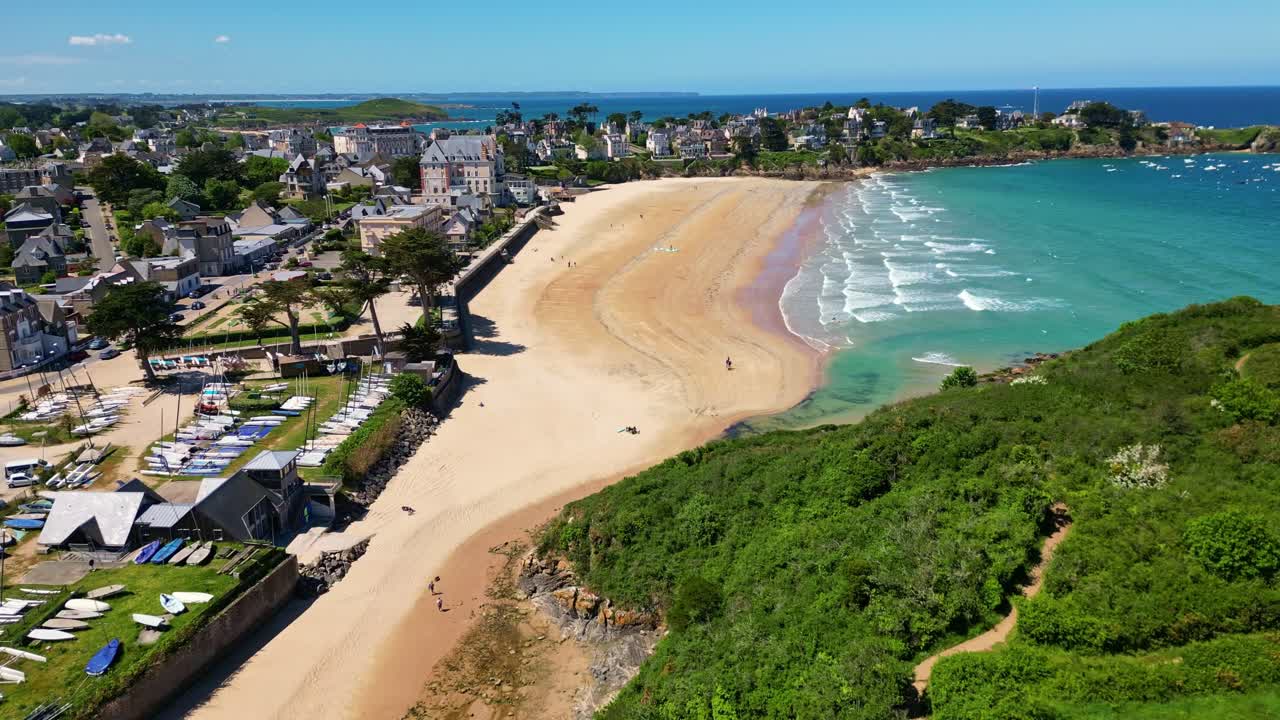 Plage de Saint-Lunaire beach, turquoise waters, coastal town and cliffs, Brittany, France. Aerial drone lateral view