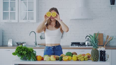 happy young woman enjoys organic fruit. beautiful woman with oranges in the kitchen on the background of many fresh vegetables and fruit.