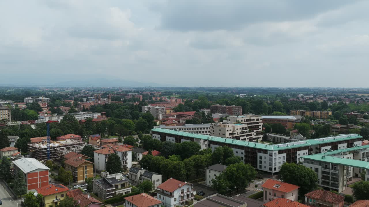 Aerial drone view of Vimercate, town in Lombardy, Italy, residential buildings, green trees, and cityscape under overcast sky, Brianza region. Copy space