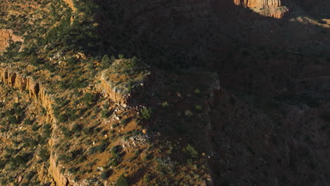 aerial view tilting over large sunlit cliffs, warm, sunny evening in utah, usa