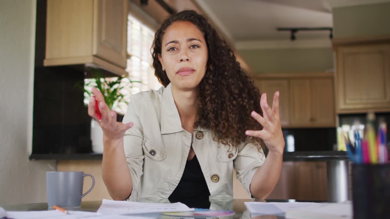 Happy biracial woman gesturing on video call in kitchen