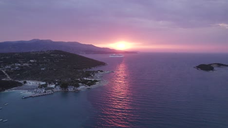 vibrant sunset with cruise ship passing by in mediterranean, aerial along ionian coastline of ksamil, albania