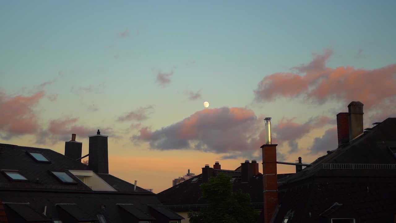 The image shows rooftops and a moon in a vibrant sky, captured in Frankfurt am Main.