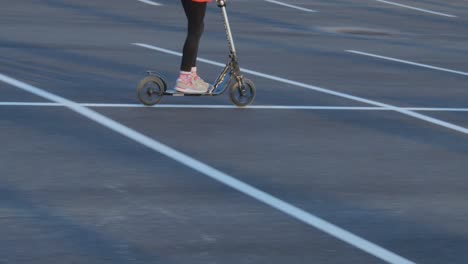 una niña monta una moto por un estacionamiento vacío