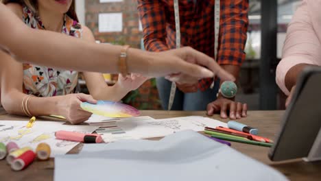 sección media de diversos diseñadores que usan tableta en una reunión de diseño en un estudio de moda, en cámara lenta