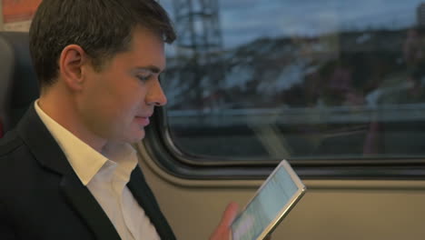 man in train laughing at tablet