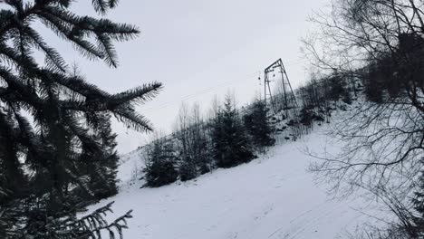 Stillgelegter-Skilift-Im-Winter-Mit-Schnee-Und-Bäumen-Im-Vordergrund