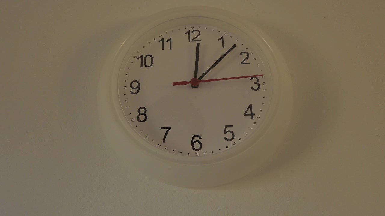 The beginning of time 12.05 am or pm, Clock hands seconds walk slowly, Close up a white wall clock.