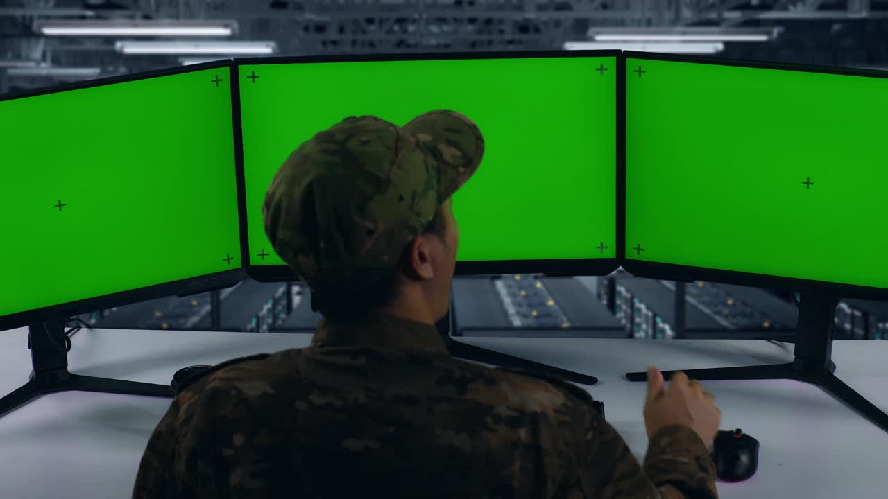 vista trasera de un militar asiático cansado bostezando antes de dormir mientras trabajaba con un simulacro de varios monitores de computadora en el centro de datos