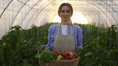 Portrait-of-a-woman-with-fresh-harvested-greens-and-peppers-in-greenhouse