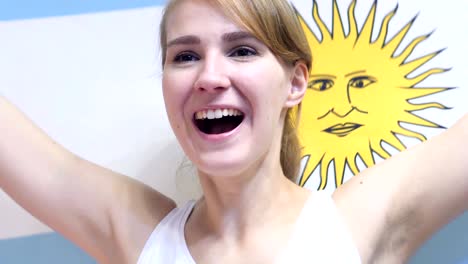 argentinian young woman celebrating while holding the flag of argentina in slow motion