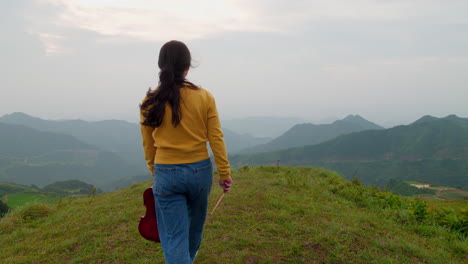 young-woman-holds-a-violin-and-walks-to-the-edge-of-a-windy-mountaintop