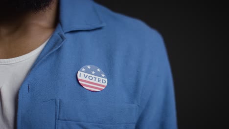 de cerca del hombre poniendo yo voté pegatina en la camisa en las elecciones estadounidenses