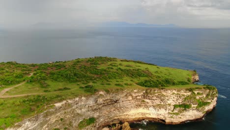 vista aérea que avanza, sobre el acantilado verde de tanjung ringgit, vista panorámica del mar de lombok, indonesia