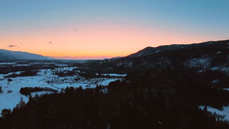 drone shot of mountains, fields, and landscape in winter at golden hour, sunrise with snow, flying over hills and fields with vibrant colors