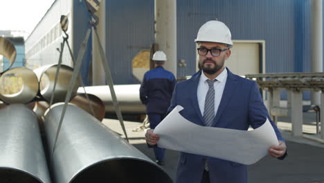 manufacturing engineer with blueprint at plant