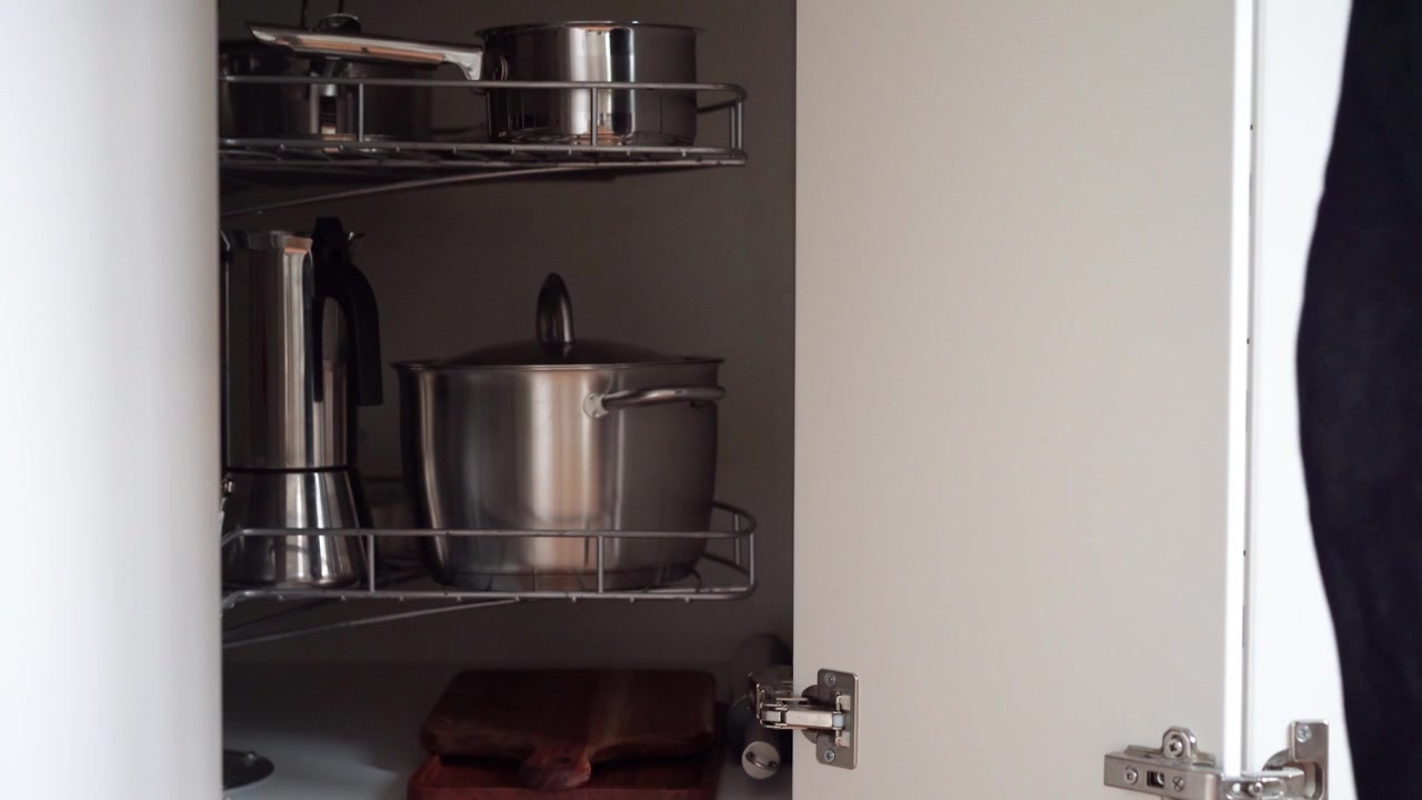Kitchen corner cabinet with lazy Susan being swung around by woman