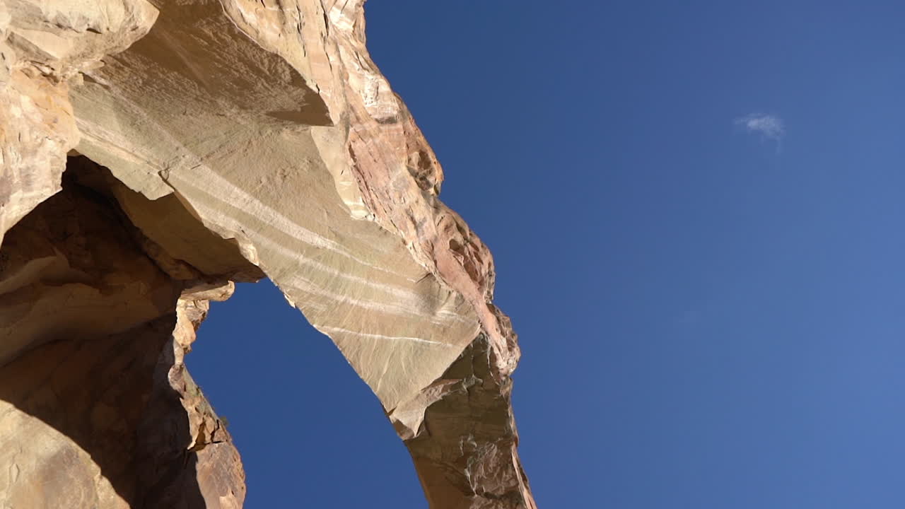 hombre emocionado en la cima de la roca bajo un impresionante arco natural levantando los brazos