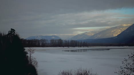 Hiperlapso-De-La-Hora-Dorada-De-Densas-Nubes-Sobre-Montañas-Cubiertas-De-Nieve-Y-El-Río-North-Thompson-Congelado-Cerca-De-Little-Fort,-BC