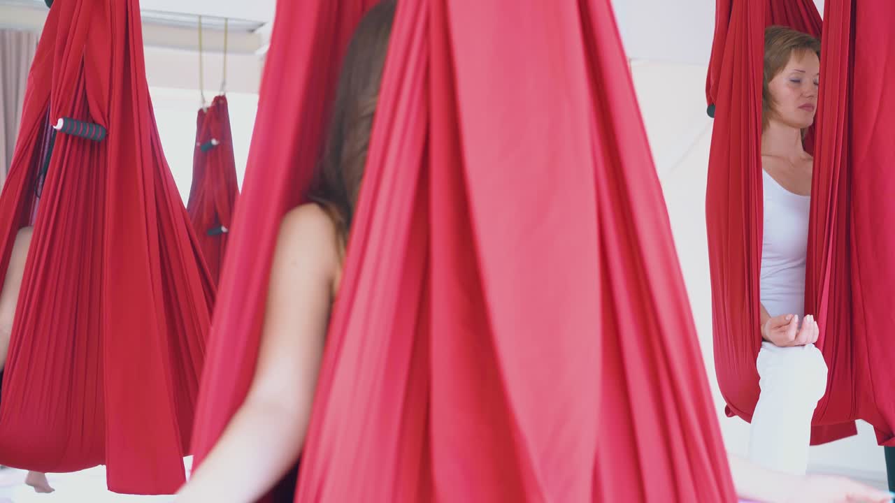 женщины расслабляются в красных гамаках с пальцами в положении мудра