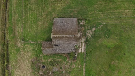 Casa-De-Campo-Abandonada-En-Medio-De-Una-Vasta-Tierra-Agrícola,-Levante-La-Vista-Aérea