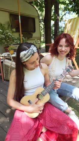 two women playing ukulele outdoors