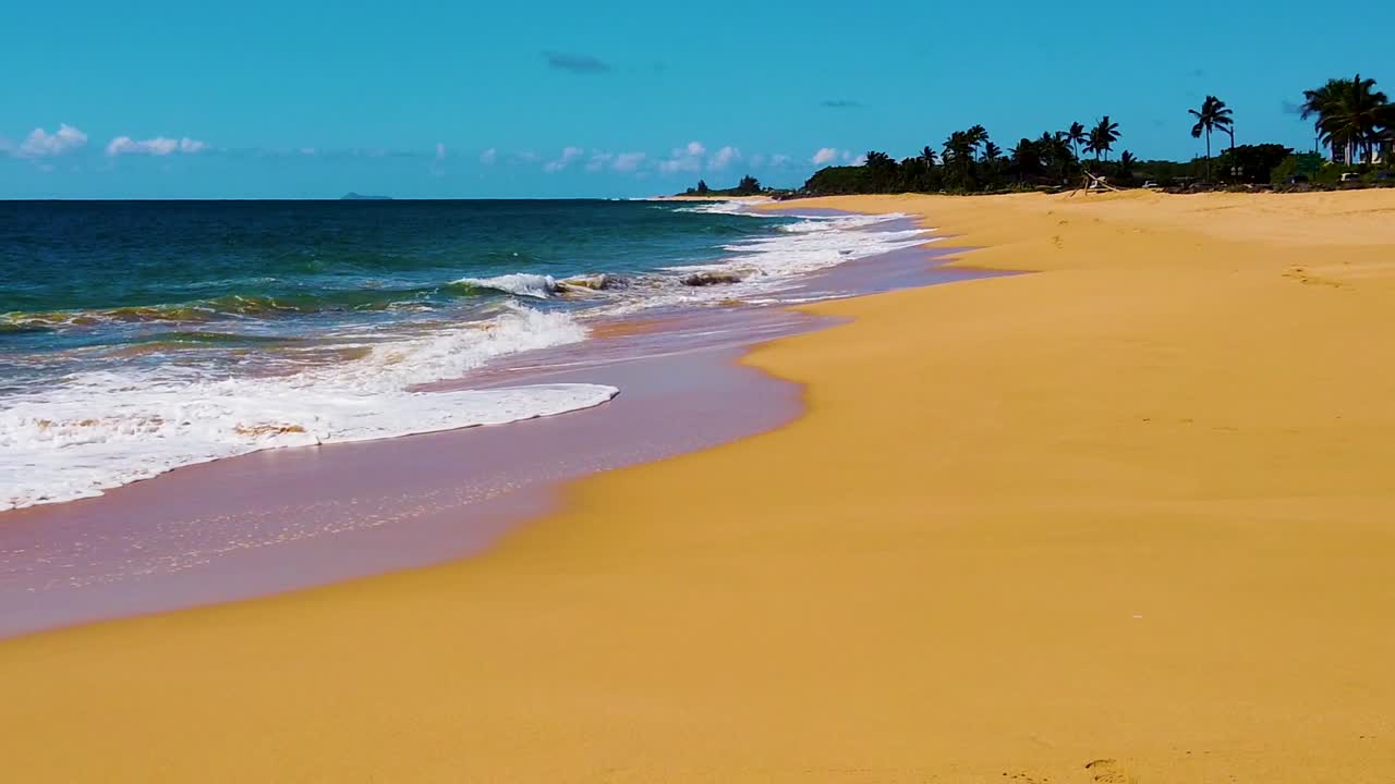 HD Hawaii Kauai, panoramica al rallentatore da destra a sinistra dalla spiaggia, oltre le onde oceaniche scintillanti e retroilluminate che si infrangono, con una persona in piedi sul bagnasciuga in lontananza e cielo parzialmente nuvoloso.