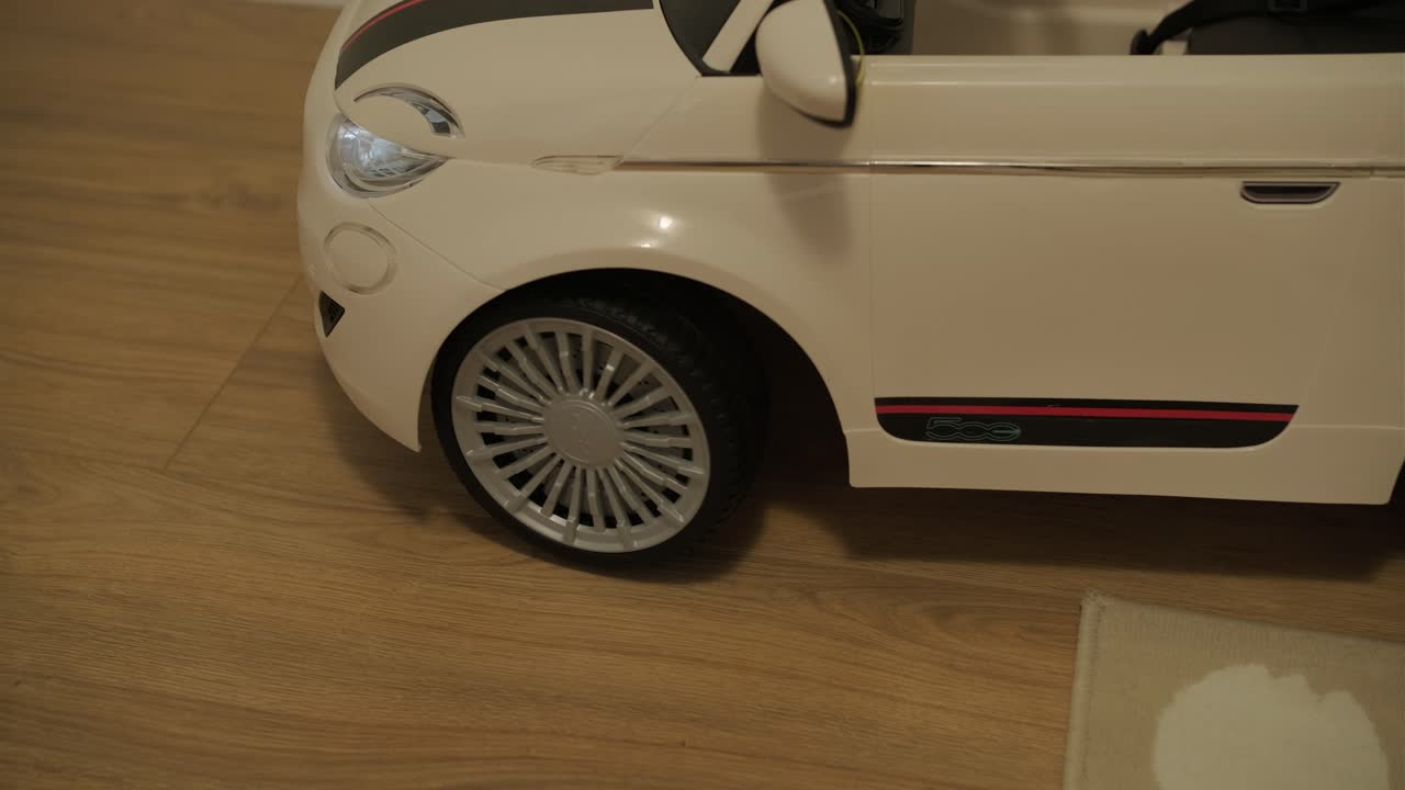 Close-up of a White Toy Car's Wheel Turning on a Wooden Floor